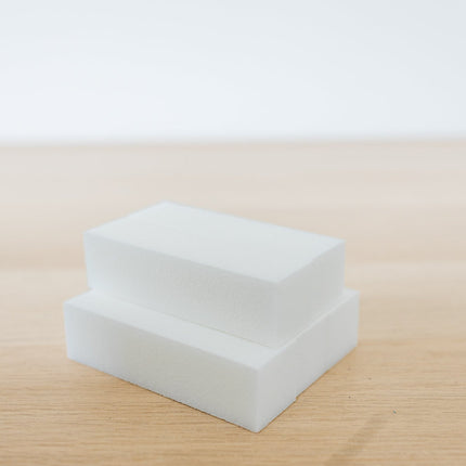 Two white square blocks on a beige surface with a light gray background