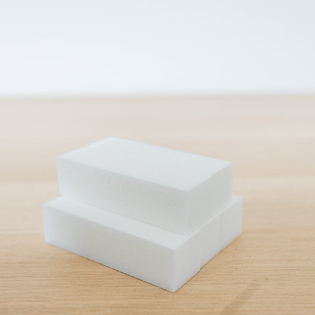 Two white square blocks on a beige surface with a light gray background